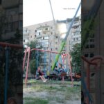Children swing on a playground beside a building struck by a Russian attack in Kyiv on July 6
